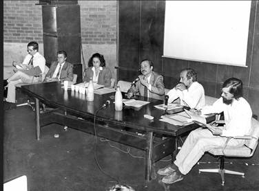 Foto em preto e branco de pessoas sentadas ao redor de uma mesa, durante Seminário da Abrasco (Reforma Sanitária), em 1987.