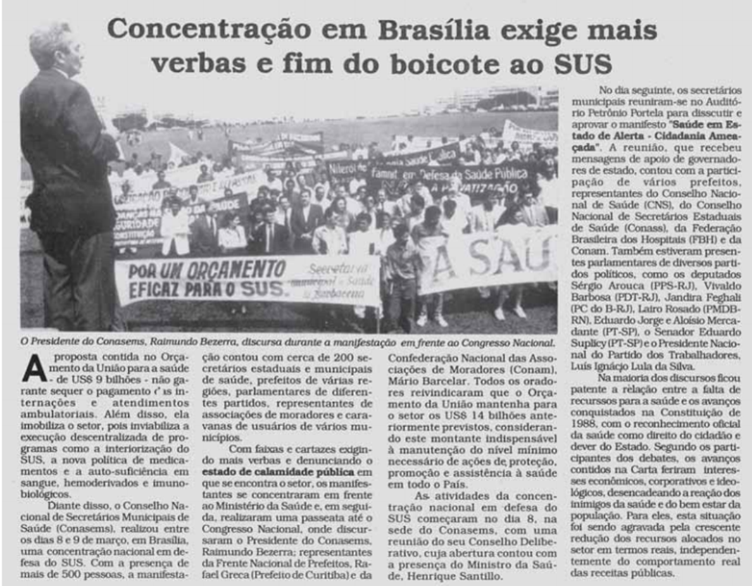 Foto preta e branca de um jornal com texto preto sobre fundo branco. Manchete: Concentração em Brasília exige mais verbas e fim do boicote ao SUS. Imagem da reportagem apresenta o presidente do Conasems, Raimundo Bezerra, discursando durante a manifestação em frente ao Congresso Nacional. 