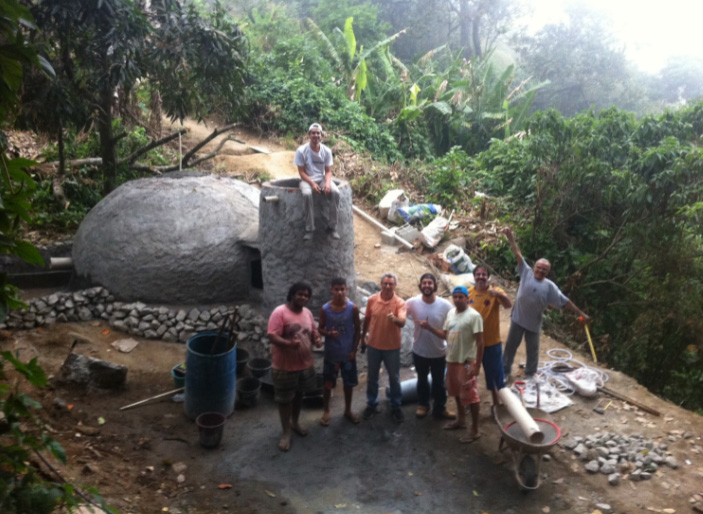 Fotografia do biodigestor e de moradores e técnicos envolvidos em sua construção no Vale Encantado, Alto da Boa Vista, Rio de Janeiro. As pessoas aparecem acenando em frente ao biodigestor ainda em construção.