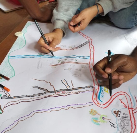 Foto de pessoas desenhando um mapa utilizando a metodologia de cartografia social. 