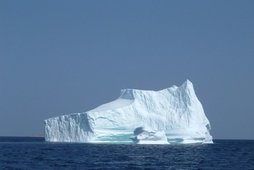 Foto da parte exposta de um iceberg no meio do oceano.